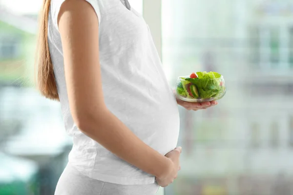 Молодая беременная женщина с овощным салатом — стоковое фото