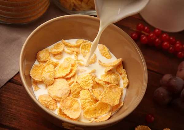 Pouring milk into tasty cornflakes — Stock Photo, Image