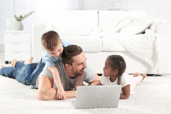 Padre con niños acostado con el ordenador portátil — Foto de Stock