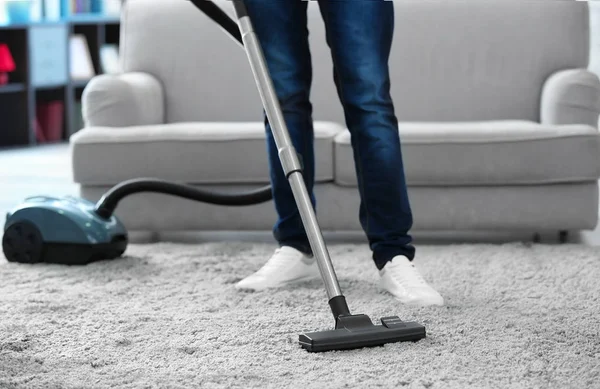 man with vacuum cleaner cleaning carpet