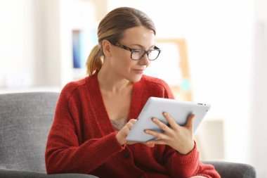 Young woman with tablet sitting on armchair clipart