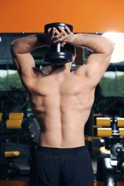 Dumbbell eğitim salonunda genç yakışıklı adamla