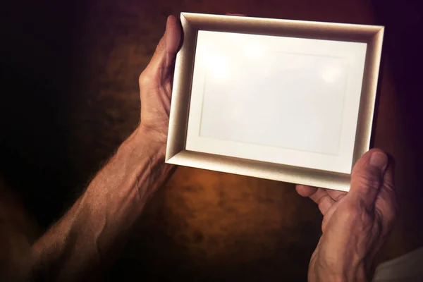 Old man holding and looking at photo frame — Stock Photo, Image
