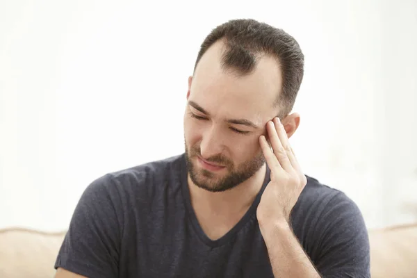 Handsome man suffering from headache at home — Stock Photo, Image