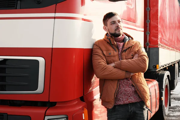 Büyük modern kamyonun yanında yakışıklı bir sürücü.