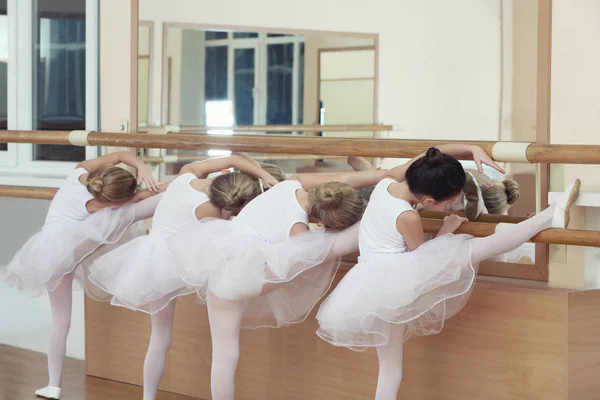 Grupo de pequenas bailarinas praticando balé usando bar na aula — Fotografia de Stock