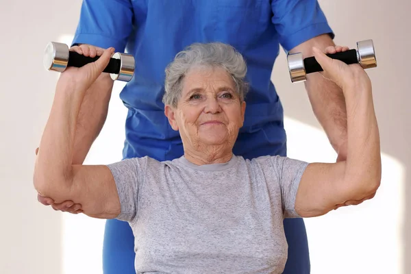 Fisioterapeuta trabalhando com paciente idoso na clínica — Fotografia de Stock