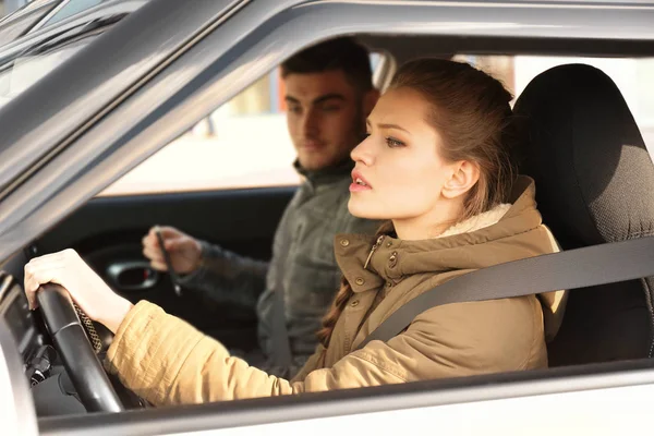 Jonge vrouw passeren van drijvende licentie examen zittend in de auto met instructeur — Stockfoto