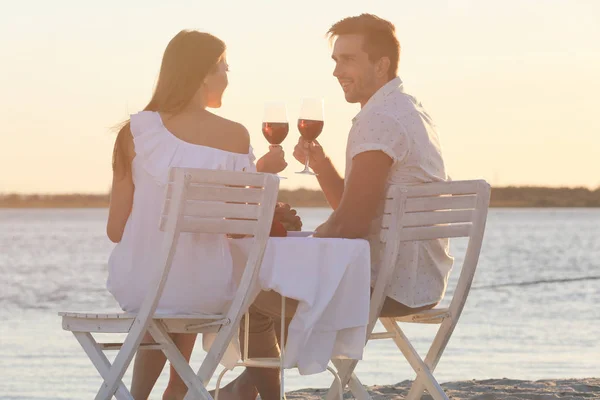 Молодая пара с вином, романтическое свидание на пляже на закате — стоковое фото