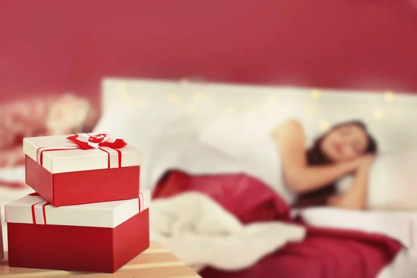 Hadiah Natal dan wanita tidur kabur di latar belakang — Stok Foto