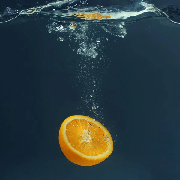 juicy orange falling in water