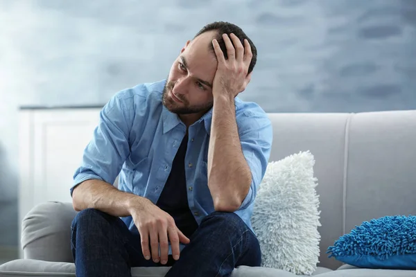 Schöner depressiver Mann sitzt zu Hause auf Sofa — Stockfoto