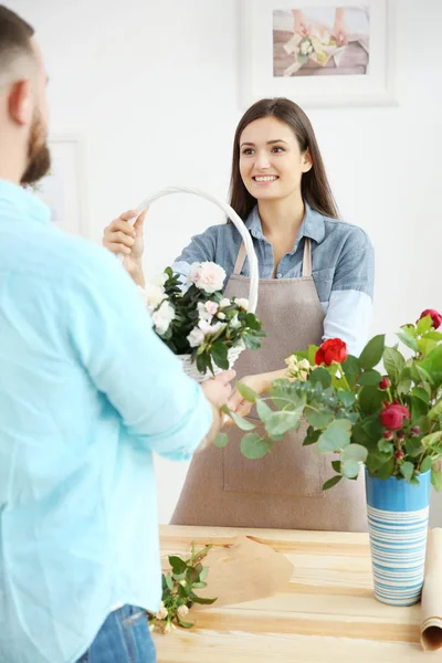 Florista dando cesta com flores para o cliente — Fotografia de Stock