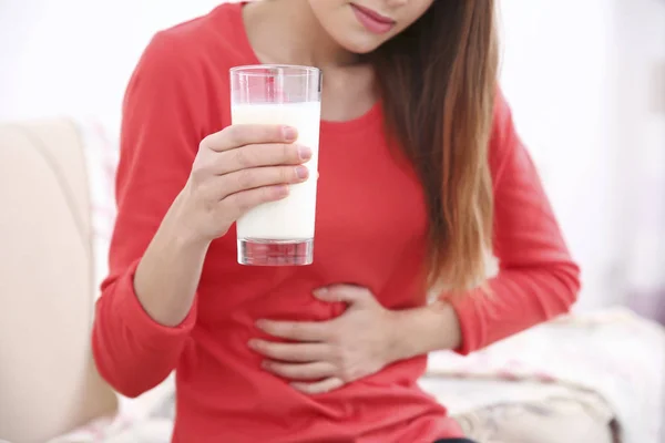 Жінка з болем у животі тримає склянку молока — стокове фото