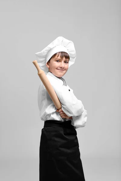 Lindo chico en uniforme de chef sobre fondo claro —  Fotos de Stock