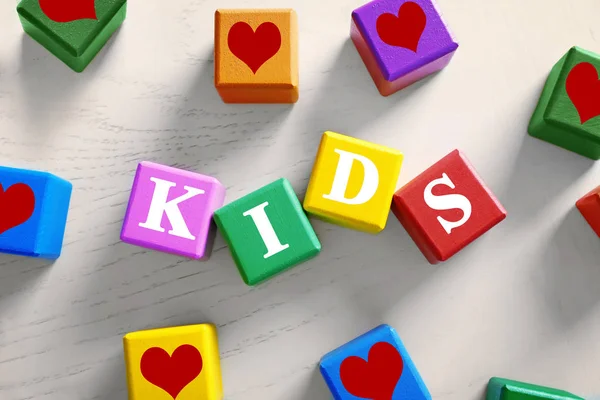 Барвисті кубики зі словом KIDS на дерев'яному фоні — стокове фото