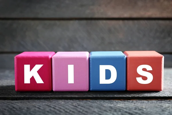 Барвисті кубики зі словом KIDS на дерев'яному фоні — стокове фото