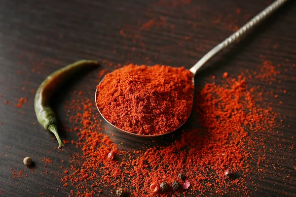 Spoon with paprika powder and chili pepper on wooden background — Stock Photo, Image