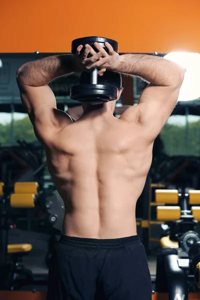 Joven hombre guapo con entrenamiento de mancuerna en el gimnasio —  Fotos de Stock