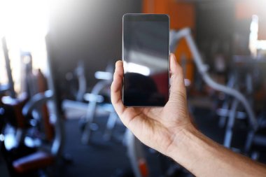 İnsan eli ile cep telefonu ve arka plan üzerinde bulanık spor salonu
