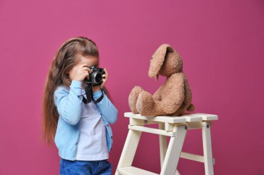 Vintage fotoğraf makinesi alarak fotoğraf renk arka plan üzerinde oyuncak ile küçük kız