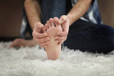 Adam podalgia evde, closeup acı