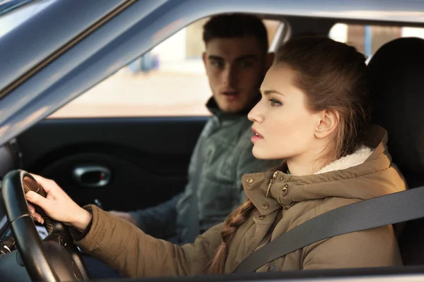 Молодая женщина сдает экзамен на водительские права, сидя в машине с инструктором — стоковое фото