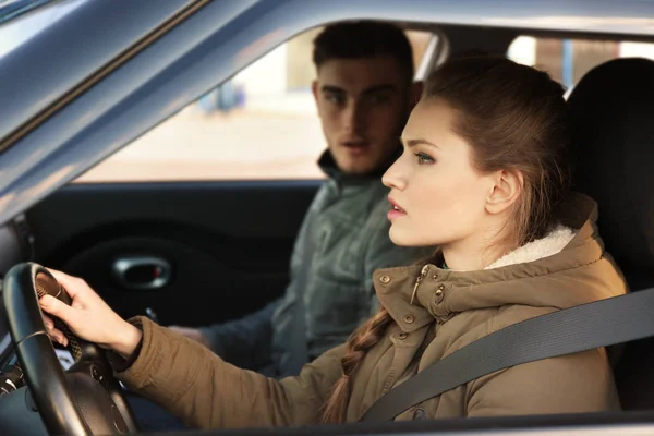 Mujer joven que pasa el examen de licencia de conducir mientras está sentado en el coche con instructor — Foto de Stock