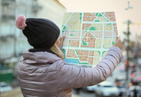 Young woman holding map on the street