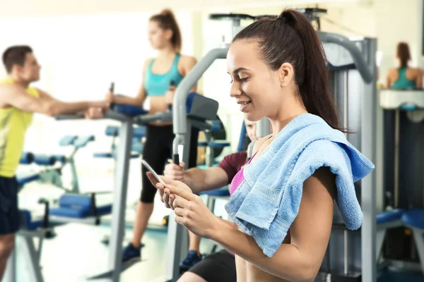 Mujer joven con teléfono celular en el gimnasio —  Fotos de Stock