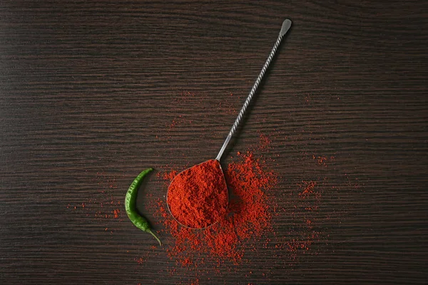 Lžíce paprikové prášek a chilli papričkou na dřevěné pozadí — Stock fotografie