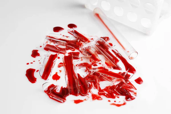 Broken test tubes with blood on white table — Stock Photo, Image