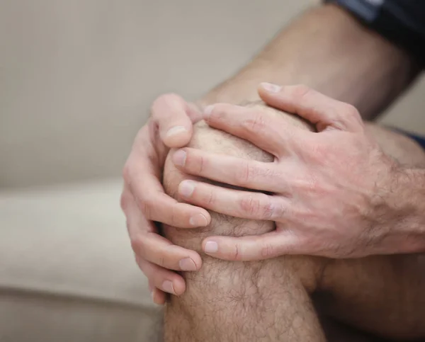 Мужчина, страдающий от боли в колене дома, крупным планом — стоковое фото