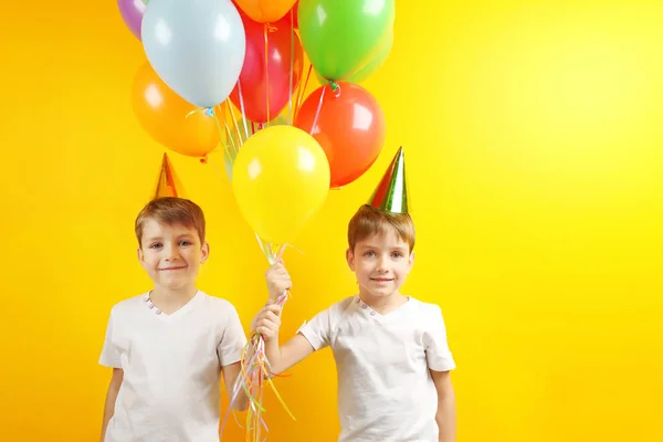 Lindos niños de cumpleaños con globos de colores sobre fondo amarillo — Foto de Stock
