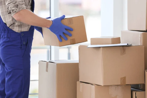 Delivery man moving boxes indoors — Stock Photo, Image