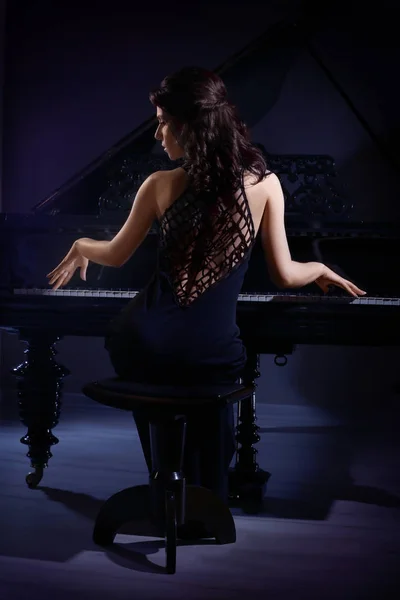 Beautiful woman posing near piano