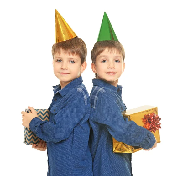 Schattige tweeling met verjaardag hoeden en presenteert op witte achtergrond — Stockfoto