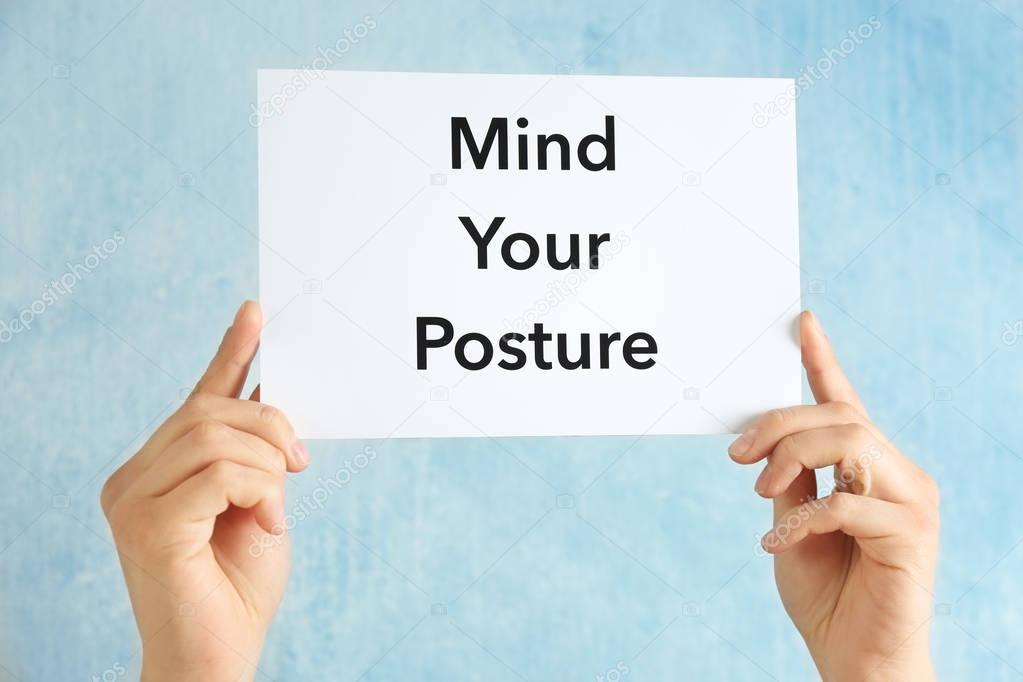 Hands holding paper with phrase MIND YOUR POSTURE on light background