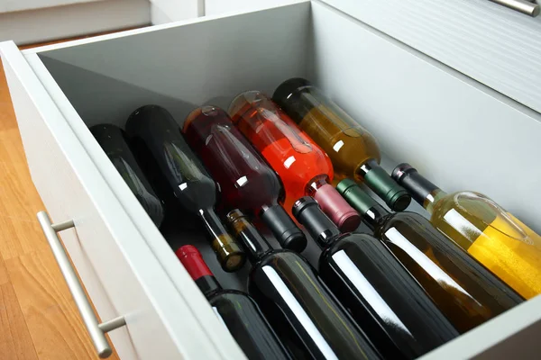 Kitchen drawer with assortment of wine bottles — Stock Photo, Image