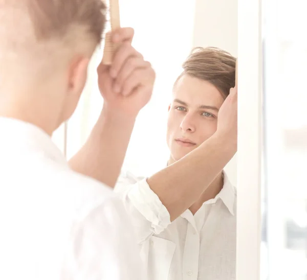 Mann kämmt Haare in Spiegelnähe — Stockfoto