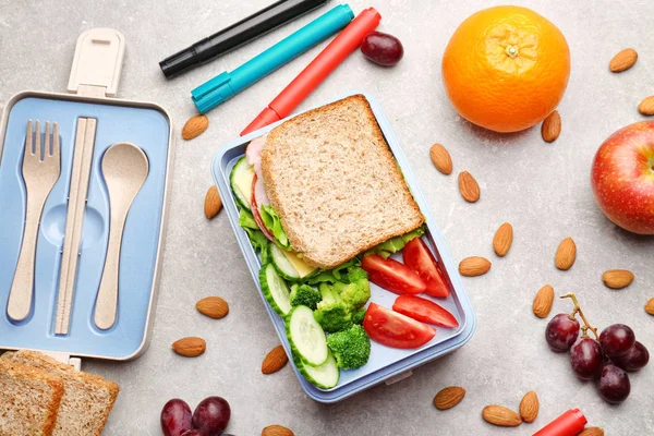 Lunch box with delicious food, fruits and almond on light textured background — Stock Photo, Image