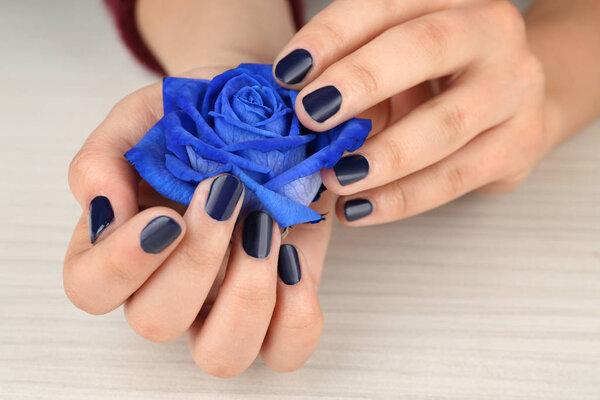 female hand with manicure holding rose 