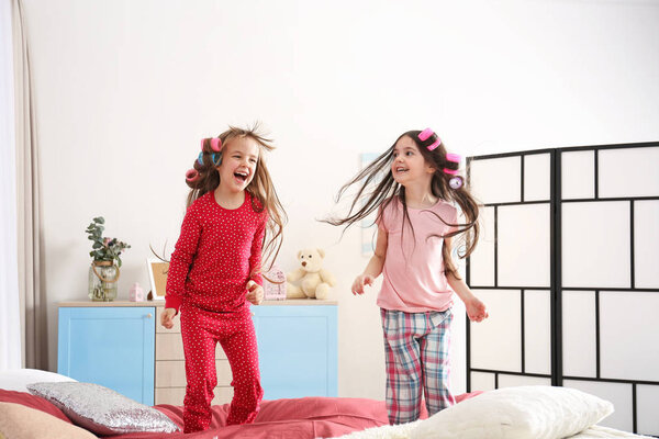 Милые маленькие девочки прыгают на кровати дома

