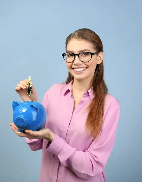 Mulher colocando dinheiro no banco porquinho — Fotografia de Stock