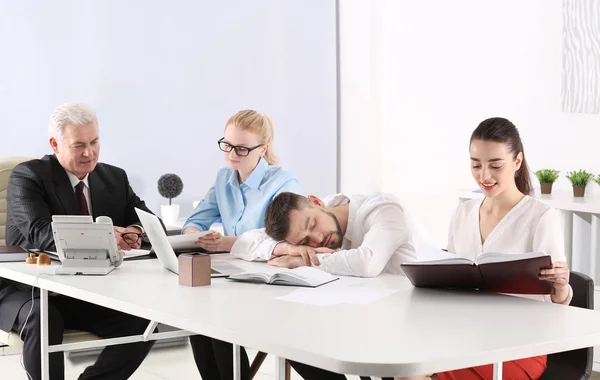Zmęczony młody człowiek śpi podczas konferencji w biurze — Zdjęcie stockowe