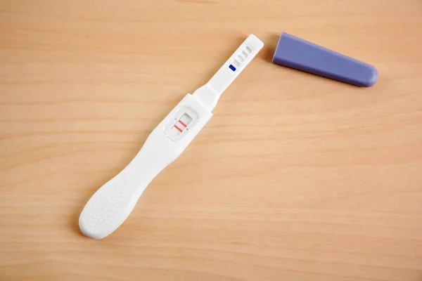 Zwangerschapstest op houten tafel — Stockfoto