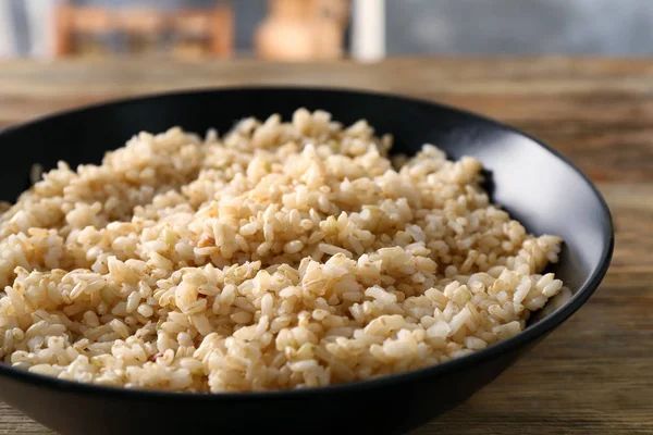Assiette avec riz brun sur table en bois — Photo