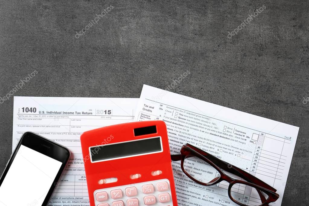 Calculator with documents and cellphone on table. Tax concept