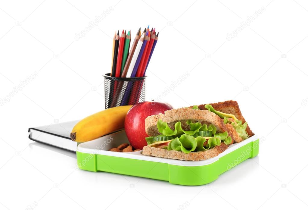 Sandwich, fresh fruits in lunch box and stationery on white background
