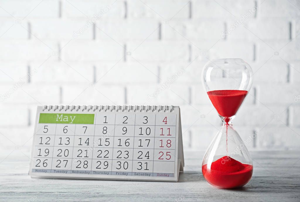 Hourglass with red sand and calendar